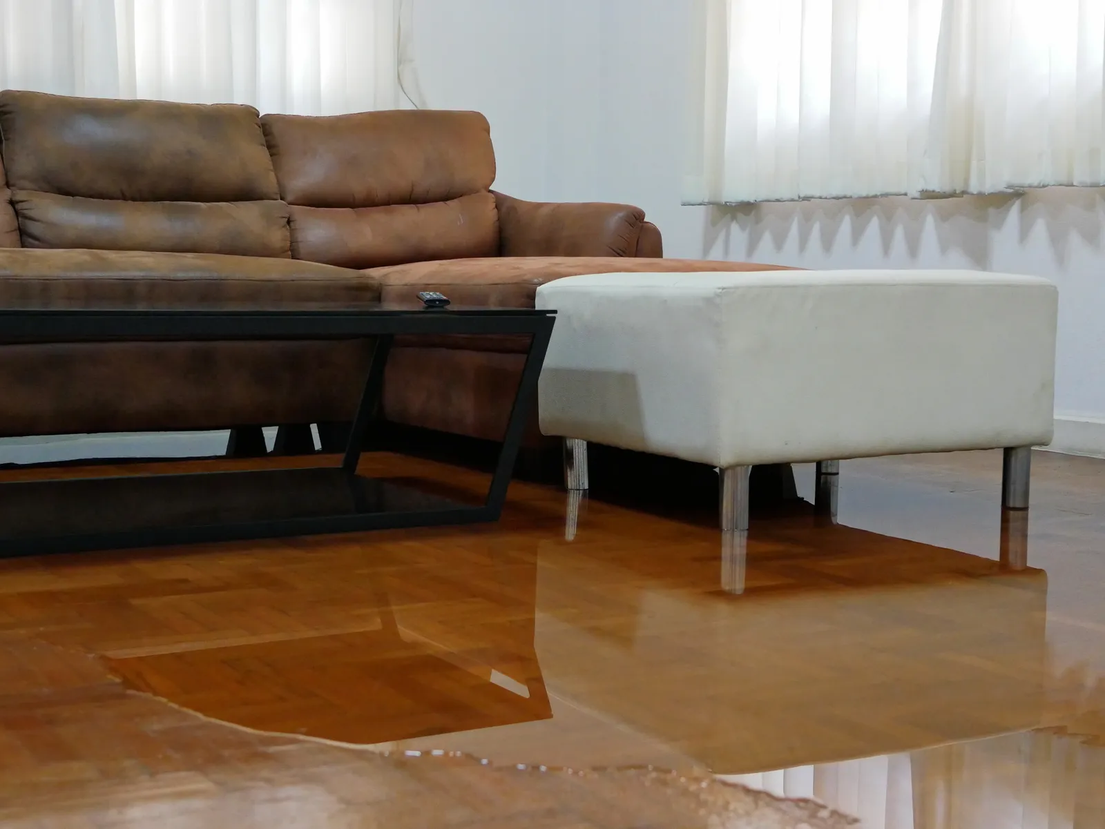 Water spreading / flooding on living room parquet floor in a house - damage caused by water leakage.